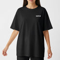 Camiseta com estampa frontal de texto "ESCAPES ME" em letras maiúsculas, localizadas próximo à área do peito esquerdo.