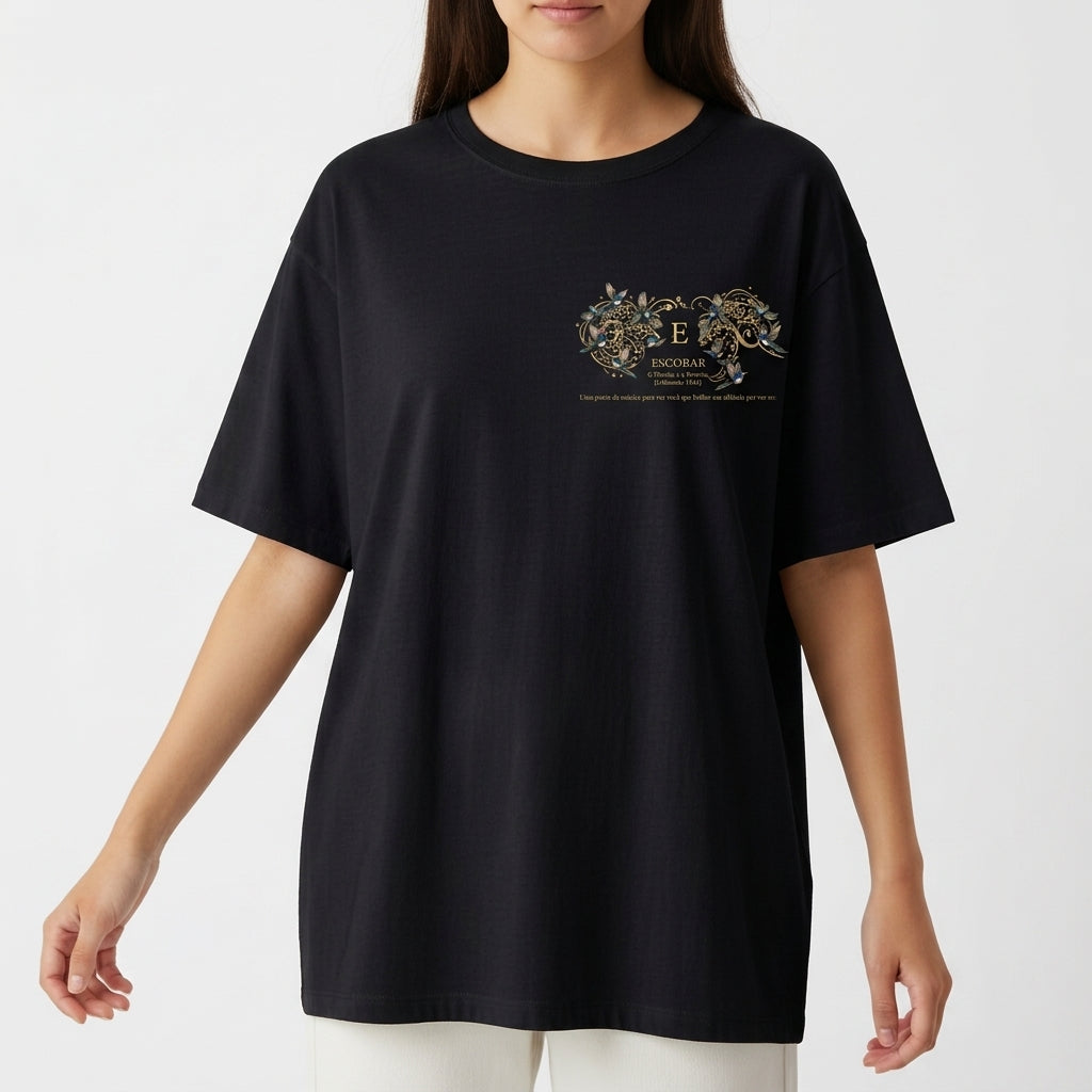 Camiseta com estampa frontal de intrincados padrões florais e texto centralizado, e estampa traseira de figura celestial com a inscrição "A PASTORA".