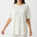 Camiseta com estampa frontal de planeta com anéis e texto curvado "MÁQUINA VOADORA" e estampa traseira de nave espacial estilizada com o mesmo texto.