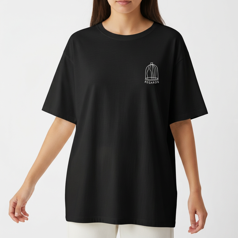Camiseta com estampa frontal de gaiola e texto pequeno e estampa traseira de mosaico colorido com coração centralizado e assinatura no canto.