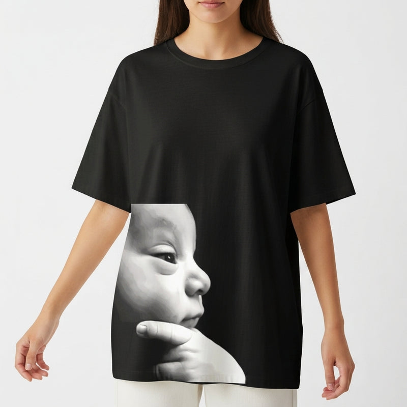 Camiseta com estampa frontal de rosto de bebê em perfil com expressão serena e dedos apoiados no queixo em estilo fotorrealista minimalista.
