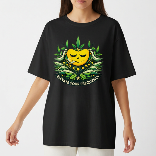 Camiseta com estampa frontal de rosto sorridente decorado com folhas e texto "Elevate Your Frequency" emoldurado por elementos naturais e estampa traseira de símbolo geométrico simples próximo à gola.