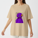 Camiseta com estampa frontal de figura abstrata roxa com cabeça redonda, olhos cruzados, boca costurada, sobre fundo com linhas onduladas pretas.