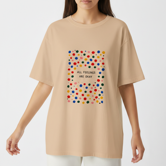 Camiseta com estampa frontal de padrão de bolinhas coloridas ao redor da frase central "ALL FEELINGS ARE OKAY", criando um visual vibrante e acolhedor.
