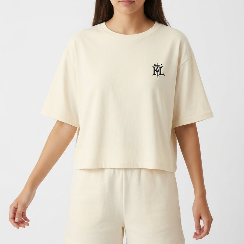 Camiseta com estampa frontal de monograma estilizado e estampa traseira de ilustração de figura crucificada sobreposta a repetição da palavra "JESUS".