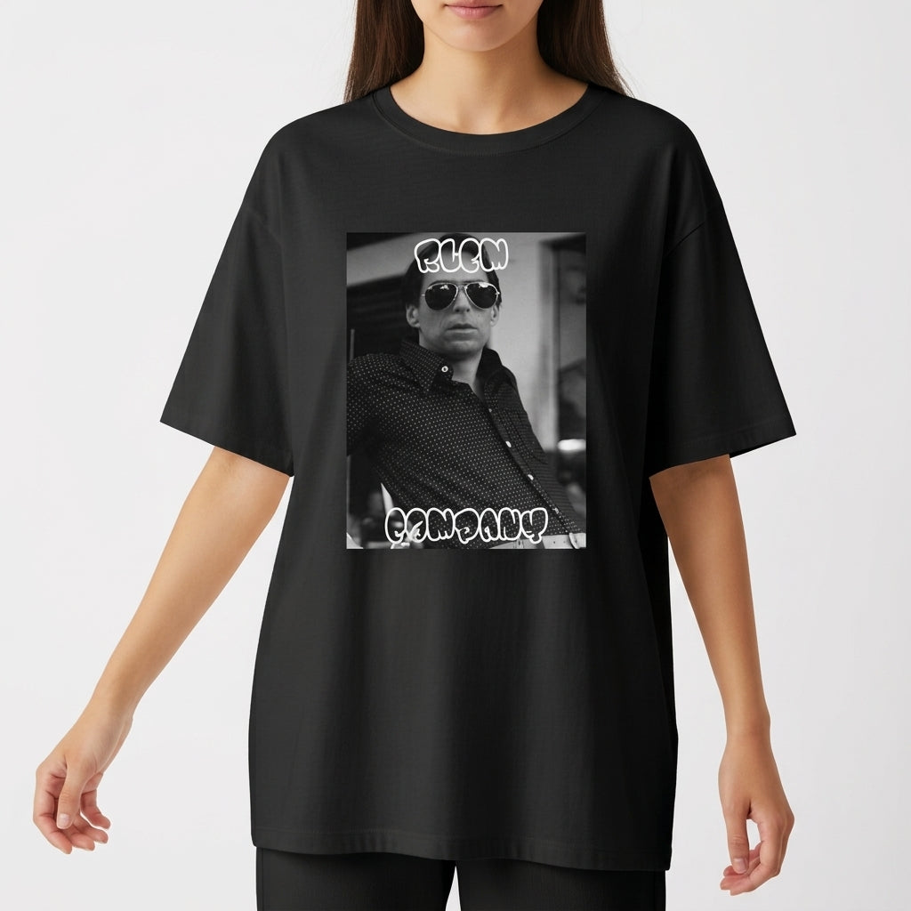 Camiseta com estampa frontal de fotografia em preto e branco de uma pessoa usando óculos escuros, com texto estilizado acima e abaixo da imagem.