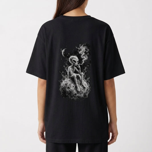 Camiseta com estampa traseira de alienígena sentado numa superfície rochosa, fumando com tranquilidade, envolto em uma atmosfera etérea e nebulosa sob a lua.