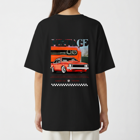 Camiseta com estampa traseira de carro vintage estilizado, com destaque para faróis e grade frontal, acompanhada da palavra "VINTAGE" e padrão quadriculado.