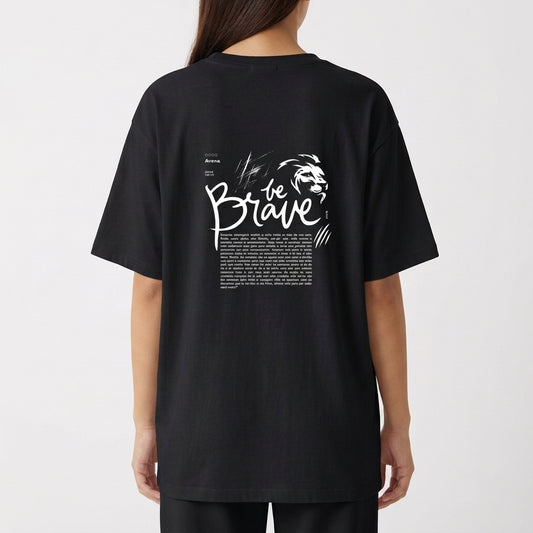 Camiseta com estampa frontal da palavra "brave" em letras estilizadas e efeito de brilho, e estampa traseira de texto "be brave" com desenho de leão.