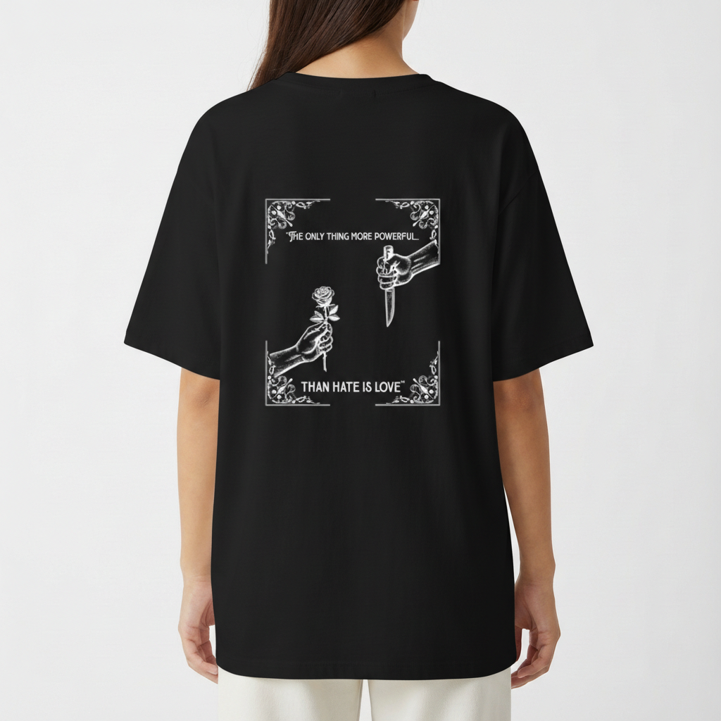 Camiseta com estampa frontal de texto em um formato oval e estampa traseira de duas mãos, uma segurando uma rosa e outra um punhal, com textos envoltos de arabescos.