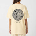 Camiseta com estampa frontal de "A. SP. PAS" alinhada verticalmente no lado esquerdo e estampa traseira de círculo com linhas concêntricas e texto.