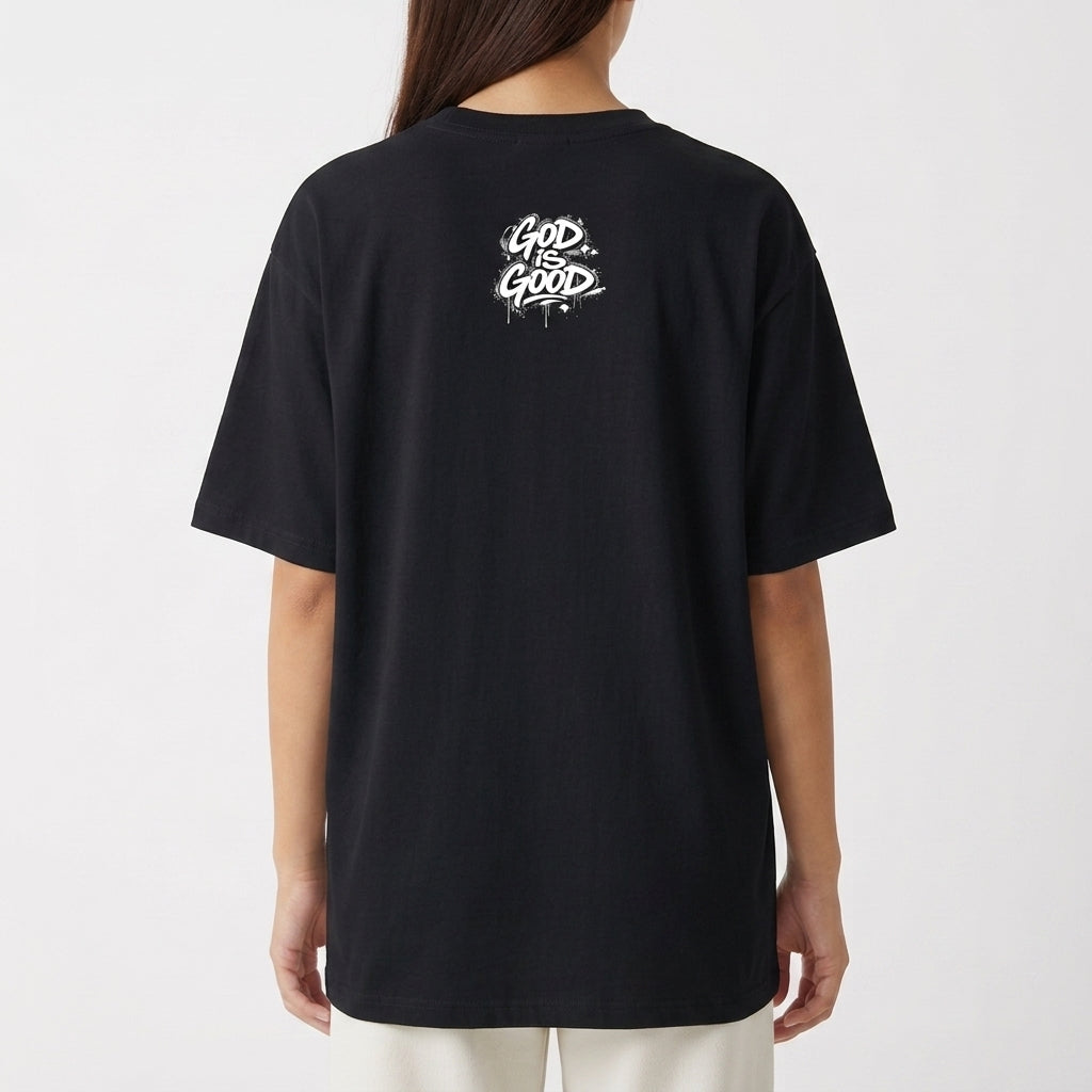 Camiseta com estampa frontal de texto 'Still Be Blessed' acompanhado de um halo, e estampa traseira de texto estilizado 'God is Good'.