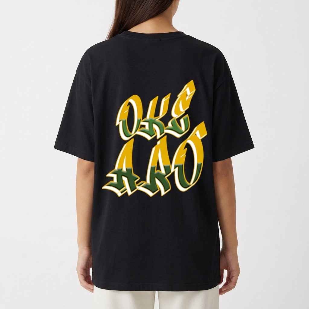 Camiseta com estampa traseira de letras grandes e estilizadas, formando a expressão "OKE AAO" com detalhes em efeito tridimensional destacando a mensagem.