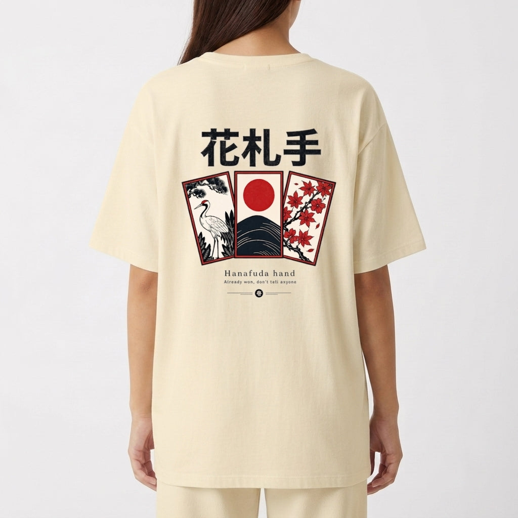 Camiseta com estampa frontal de escrita estilizada "Haganne" e estampa traseira com cartões de Hanafuda, garça, montanha e grafismos japoneses.