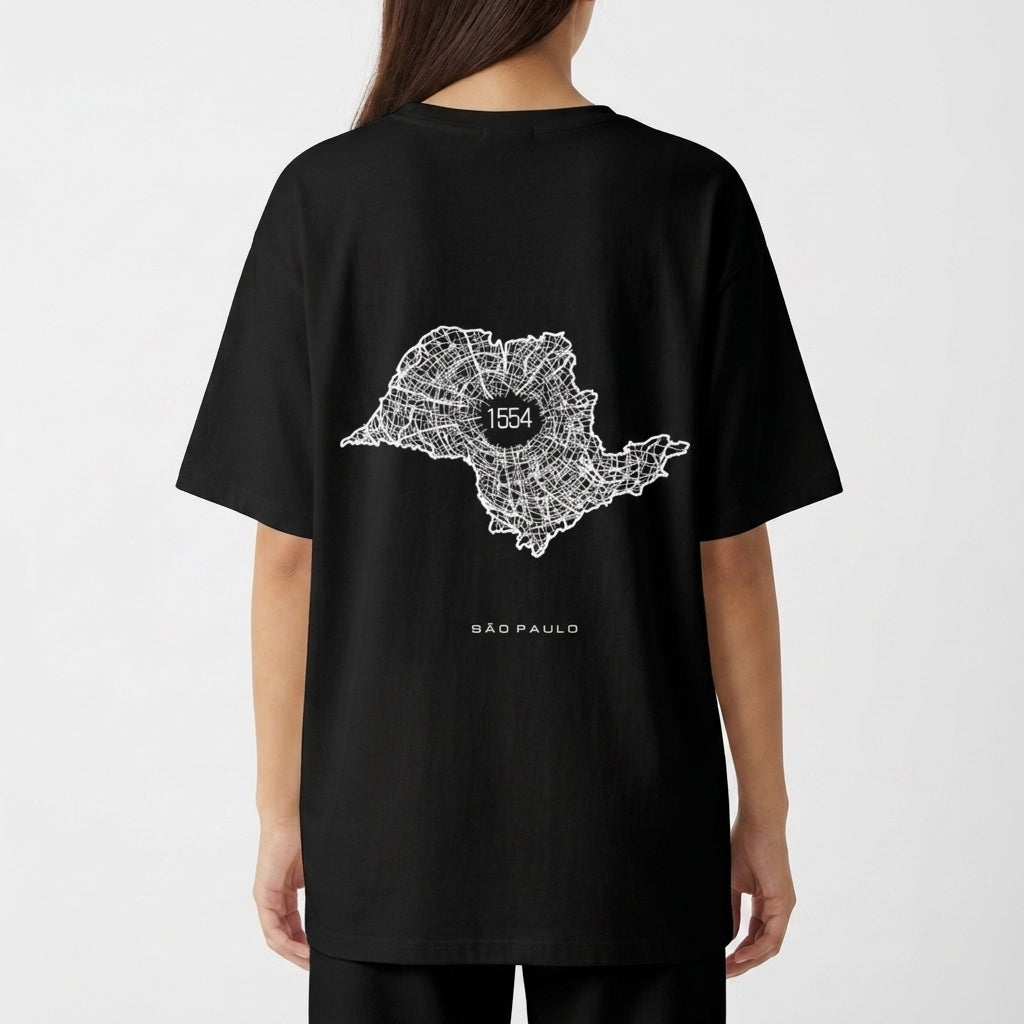 Camiseta com estampa frontal de texto verticalizado "A. SP. PAS" e estampa traseira de mapa estilizado com "1554" no centro, acompanhado de "São Paulo".