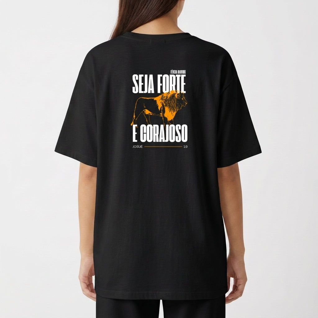 Camiseta com estampa frontal de texto pequeno discreto e estampa traseira de leão imponente com frases encorajadoras acima e abaixo da imagem.
