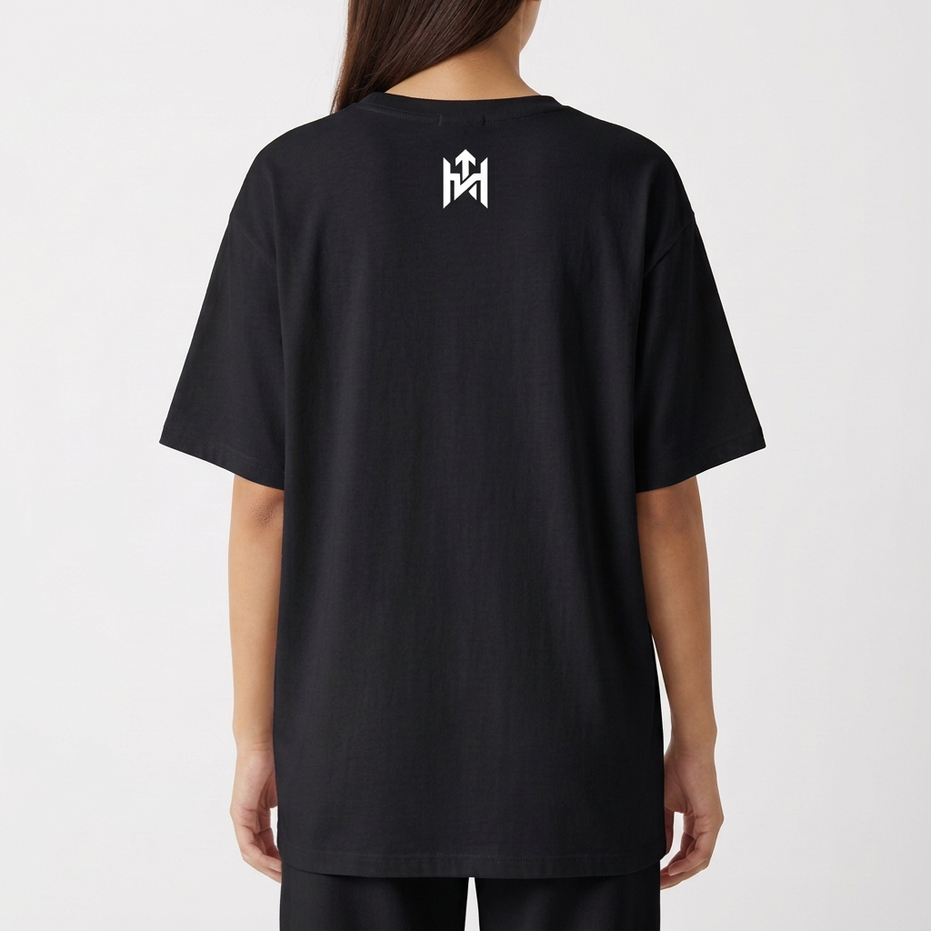 Camiseta com estampa frontal de rosto sorridente decorado com folhas e texto "Elevate Your Frequency" emoldurado por elementos naturais e estampa traseira de símbolo geométrico simples próximo à gola.