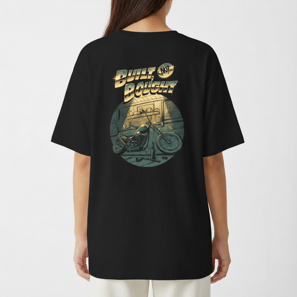 Camiseta com estampa frontal de texto pequeno e detalhe gráfico e estampa traseira de moto estilizada em garagem com texto em destaque acima.