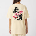 Camiseta com estampa frontal de texto "YAMA JIU JITSU" em letras pequenas e estampa traseira de caracteres japoneses grandes com flores estilizadas.
