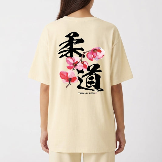 Camiseta com estampa frontal de texto "YAMA JIU JITSU" em letras pequenas e estampa traseira de caracteres japoneses grandes com flores estilizadas.