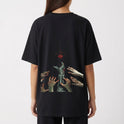Camiseta com estampa frontal de dois personagens e o texto "Fullmetal Alchemist Brotherhood" e estampa traseira de mão metálica e várias mãos alcançando um brilho.