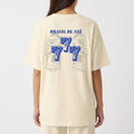 Camiseta com estampa frontal de brasão estilizado e estampa traseira de rosto tribal com "Brasil de Axé" acima e o número "777" em destaque.