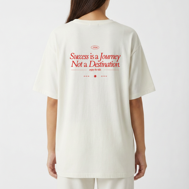 Camiseta com estampa traseira de texto estilizado "Success is a Journey Not a Destination", incluindo o ano "2026" e a frase "enjoy the ride".