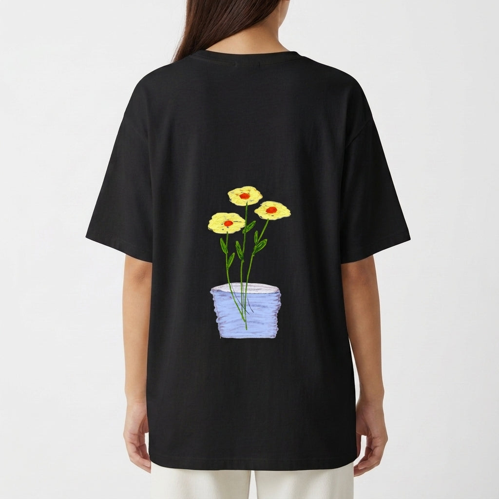 Camiseta com estampa frontal de texto em letras simples "Il raccolto è inevitabile." e estampa traseira de vaso azul com três flores amarelas e caule verde.