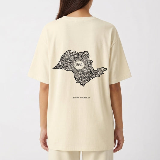 Camiseta com estampa frontal de texto vertical "A.SP.PAS" e estampa traseira de mapa em linhas com "1554" ao centro e "São Paulo" abaixo.