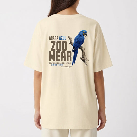 Camiseta com estampa frontal de arara azul em postura lateral com texto circular pequeno e estampa traseira de arara azul maior com texto "ZOOWEAR".