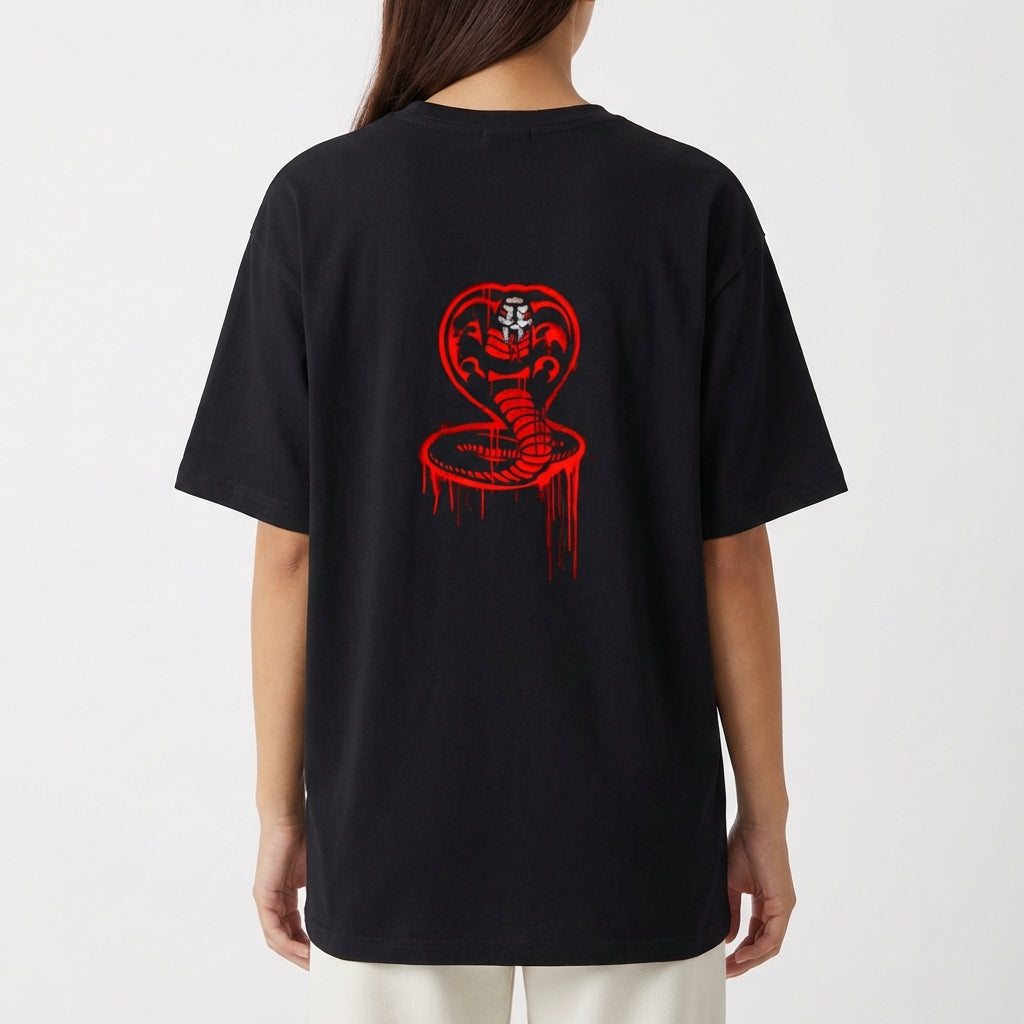 Camiseta com estampa frontal de letras estilizadas "No Mercy Club" com efeito escorrido e estampa traseira de uma cobra com capuz erguido e detalhes geométricos.
