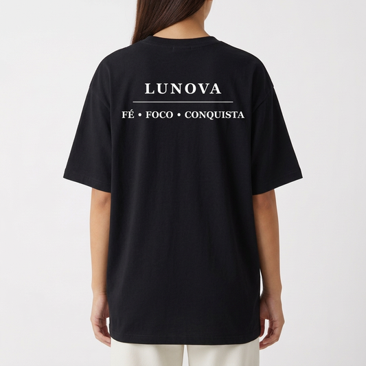 Camiseta com estampa frontal de uma cruz estilizada com asas abertas e estampa traseira de palavra "LUNOVA" seguida por "FÉ • FOCO • CONQUISTA".