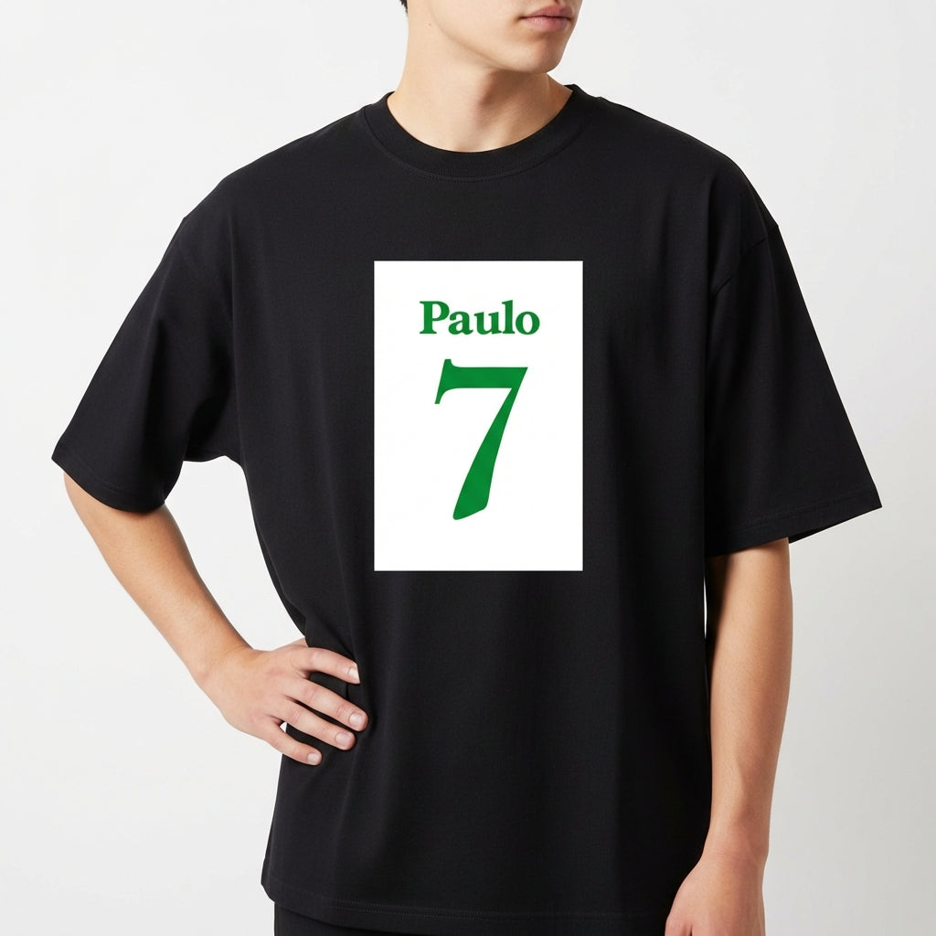 Camiseta com estampa frontal de nome "Paulo" acima do número "7", ambos em fonte estilizada, sugerindo uma temática esportiva ou personalizada.