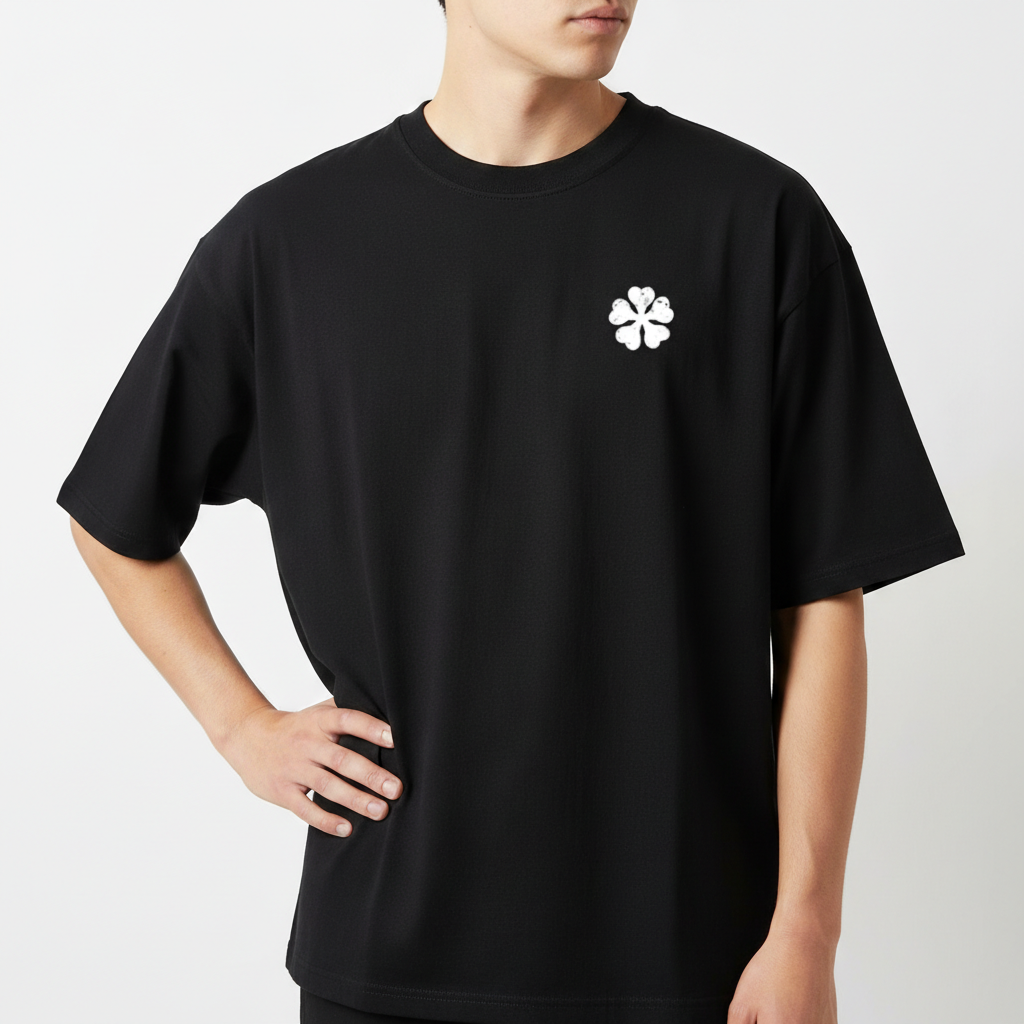 Camiseta com estampa frontal de trevo quádruplo estilizado e estampa traseira de arte em quadrinhos com personagem em recortes verticais e texto em japonês.