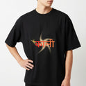Camiseta com estampa frontal de texto em outra língua sobre um padrão geométrico com estrela amarela e estampa traseira de uma figura detalhada com adornos.
