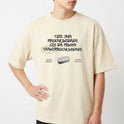 Camiseta com estampa frontal de lettering com mensagem de afirmação e imagem de lâmina, e estampa traseira de logotipo circular com ilustração central.