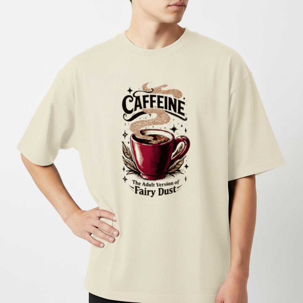 Camiseta com estampa frontal de uma xícara de café com vapor, rodeada por estrelas, a palavra "CAFFEINE" acima e a frase "The Adult Version of Fairy Dust" abaixo.