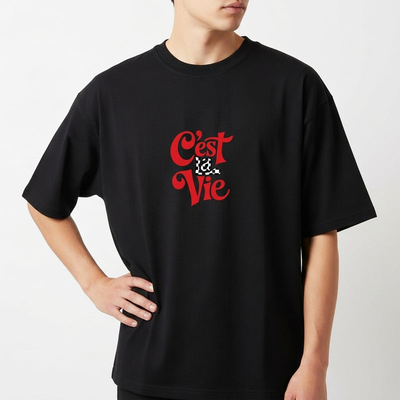 Camiseta com estampa frontal de frase estilizada "C'est La Vie" em tipografia artística, destacando-se ao centro.