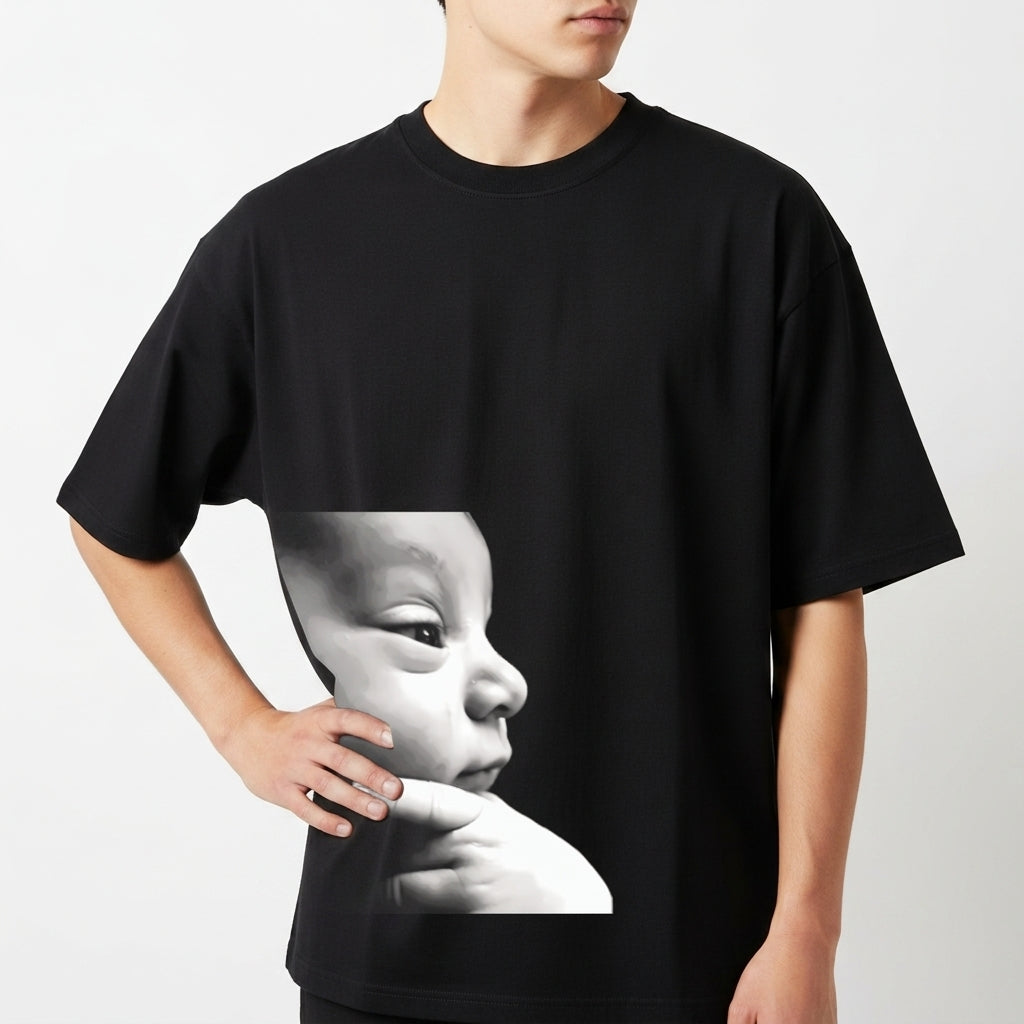 Camiseta com estampa frontal de rosto de bebê em perfil com expressão serena e dedos apoiados no queixo em estilo fotorrealista minimalista.