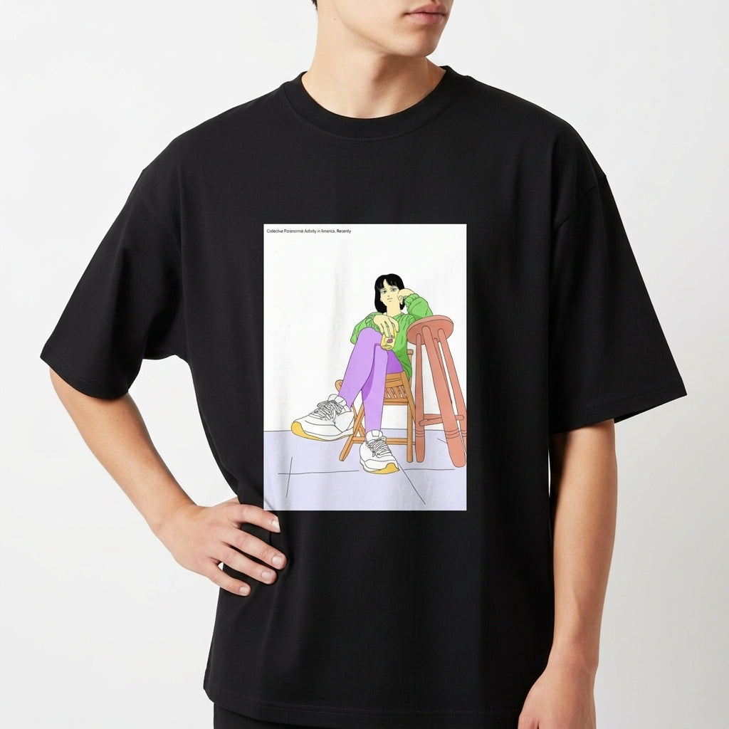 Camiseta com estampa frontal de uma figura feminina sentada de forma relaxada em uma cadeira, usando roupas casuais e tênis, sobre superfície quadrada.