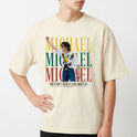 Camiseta com estampa frontal de figura central performática sobreposta a letras grandes em camadas, acima de frase estilizada na parte inferior.