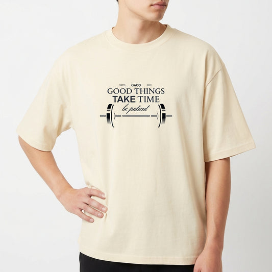 Camiseta com estampa frontal de uma barra de peso acompanhada da frase "GOOD THINGS TAKE TIME, be patient", decorando o centro com estilo motivacional.