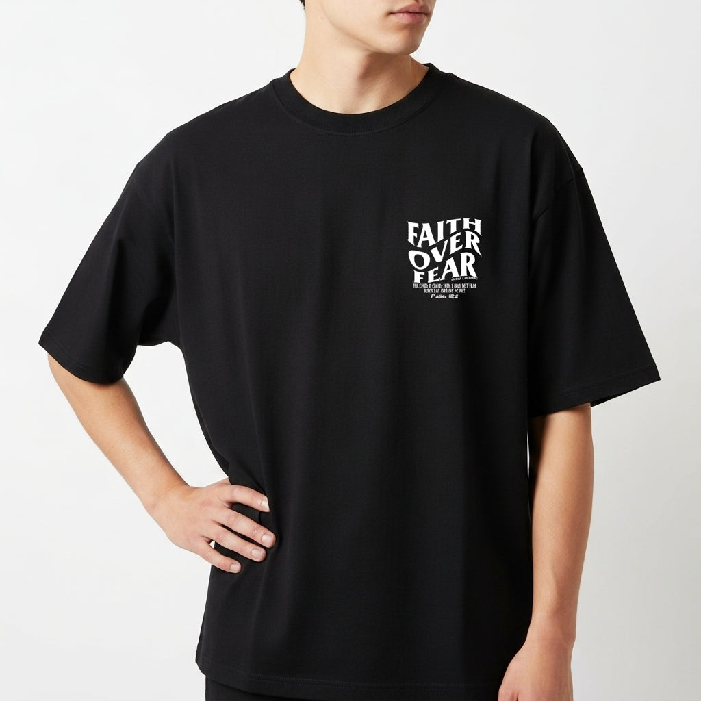 Camiseta com estampa frontal de "Faith Over Fear" com detalhes em texto pequeno e estampa traseira de "Faith Over Fear" acompanhada de citação extensa.