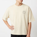 Camiseta com estampa frontal de símbolo circular estilizado e estampa traseira de desenho detalhado de personagem com adereços e expressão séria.
