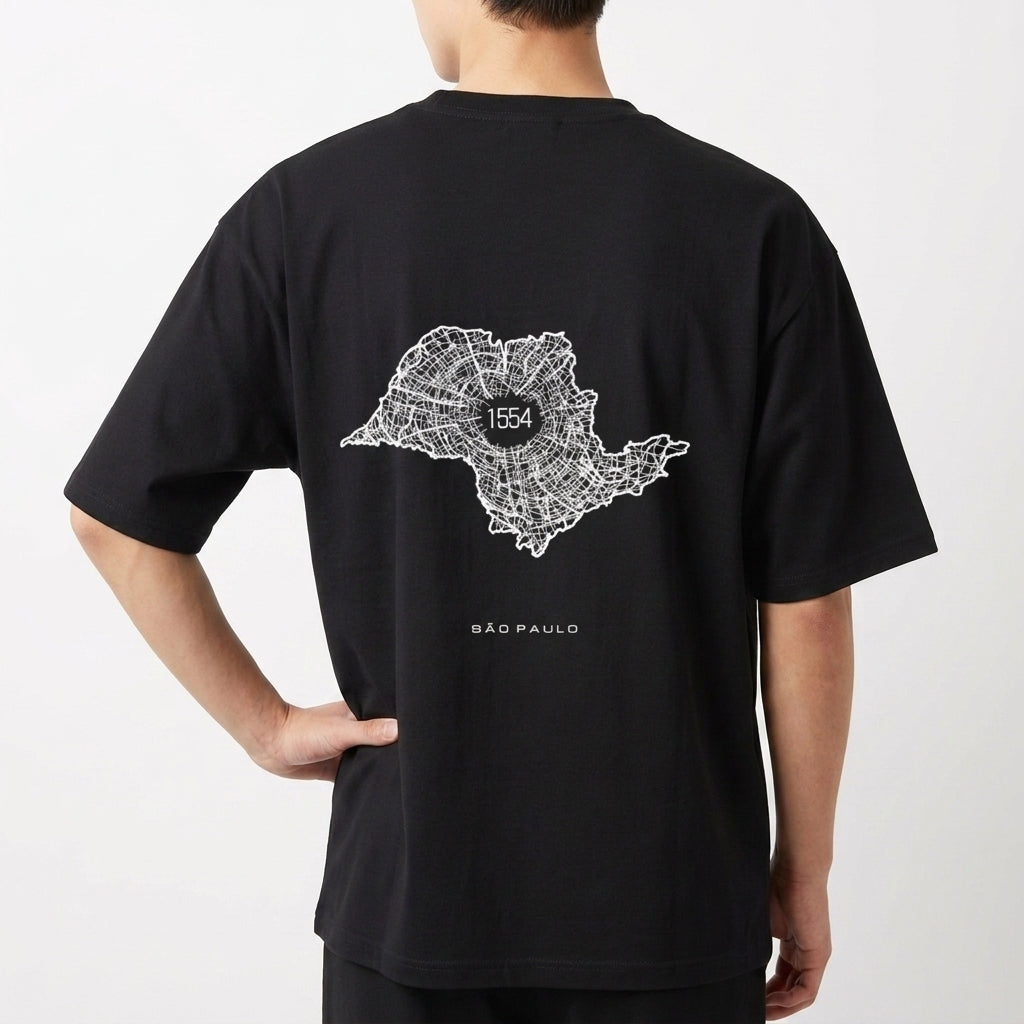 Camiseta com estampa frontal de texto verticalizado "A. SP. PAS" e estampa traseira de mapa estilizado com "1554" no centro, acompanhado de "São Paulo".