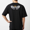 Camiseta com estampa frontal de um pequeno símbolo de leão com coroa e estampa traseira de asas estilizadas com a palavra "Blessed" e auréola acima.