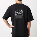 Camiseta com estampa frontal da palavra "brave" em letras estilizadas e efeito de brilho, e estampa traseira de texto "be brave" com desenho de leão.
