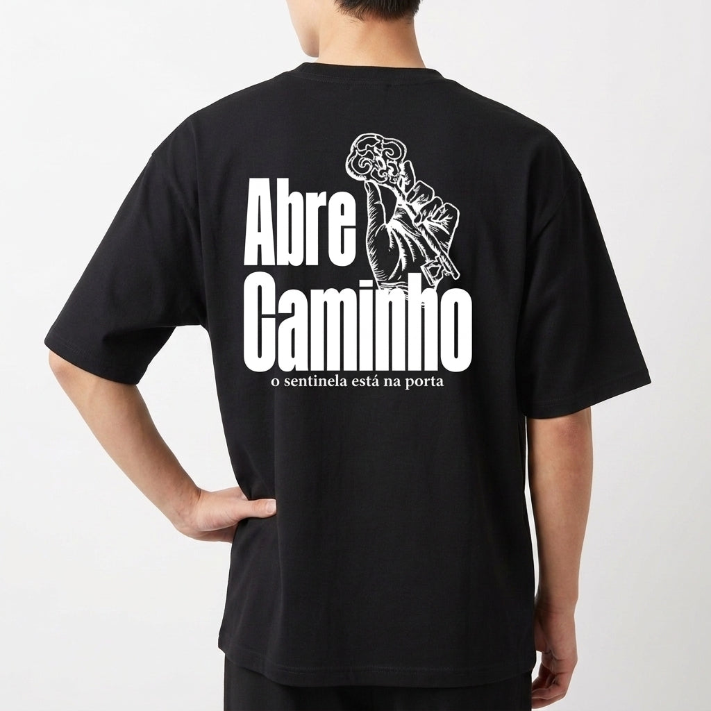 Camiseta com estampa frontal de duas chaves cruzadas estilizadas e estampa traseira de mão segurando chave com texto "Abre Caminho, o sentinela está na porta".