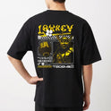 Camiseta com estampa frontal de duas mãos cruzadas segurando um controle de videogame e estampa traseira de design futurista com samurai e texto gráfico.