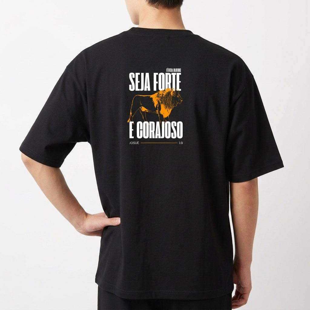 Camiseta com estampa frontal de texto pequeno discreto e estampa traseira de leão imponente com frases encorajadoras acima e abaixo da imagem.